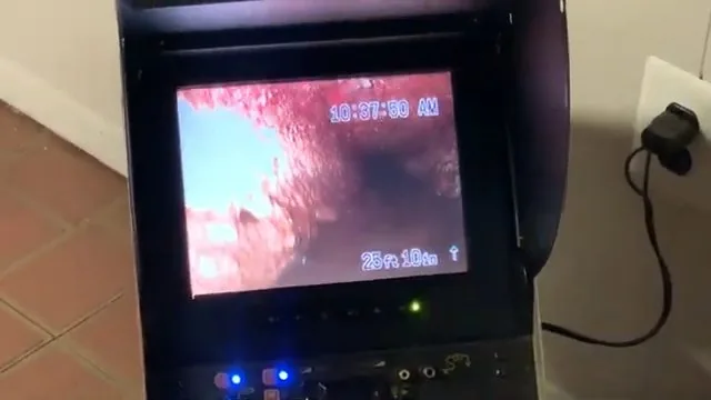 Hand pointing to a blockage on a sewer camera monitor