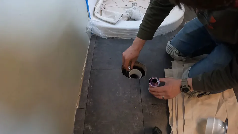 Plumber working at the toilet flange opening in a bathroom floor