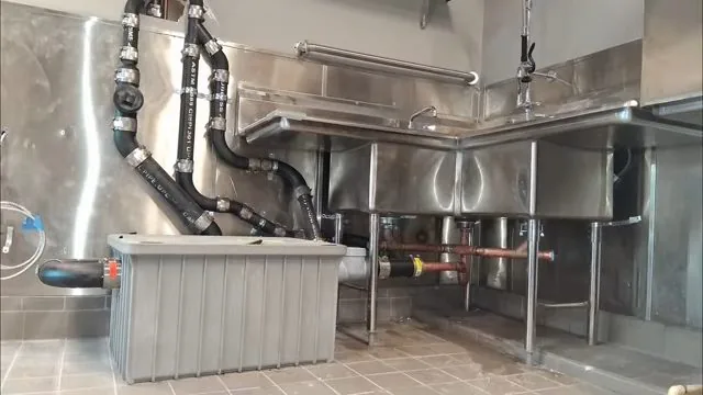 Stainless commercial kitchen with a three-compartment sink and grease trap