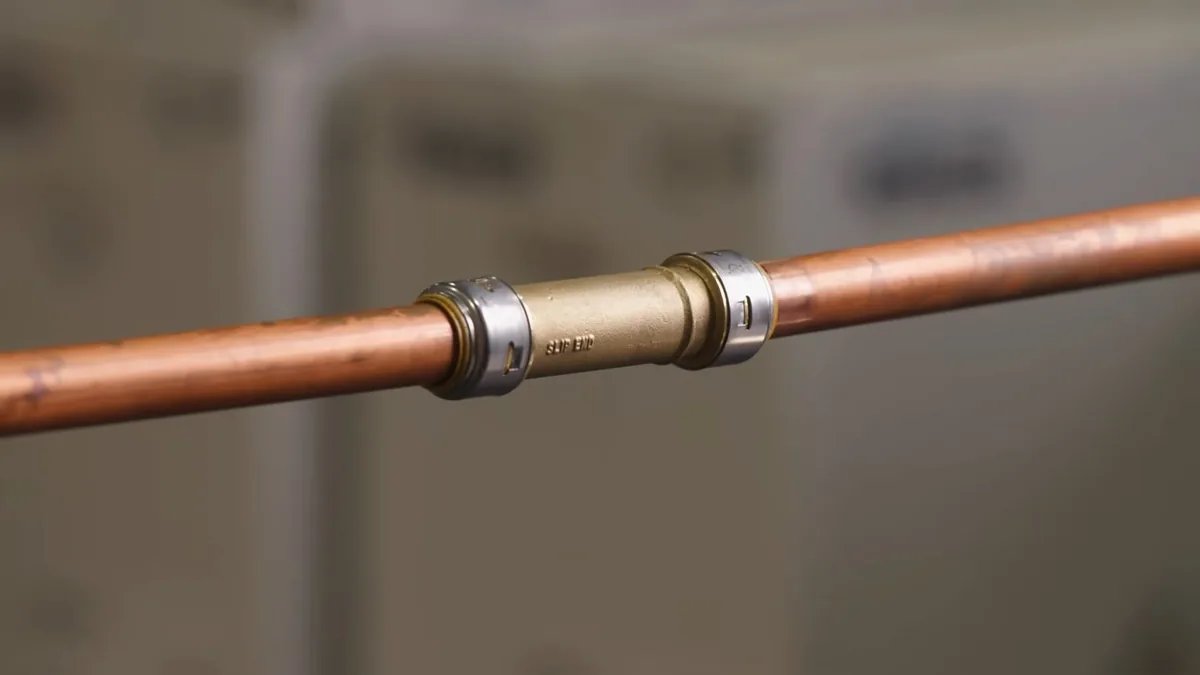 Copper pipe joined with a press coupling against a soft background