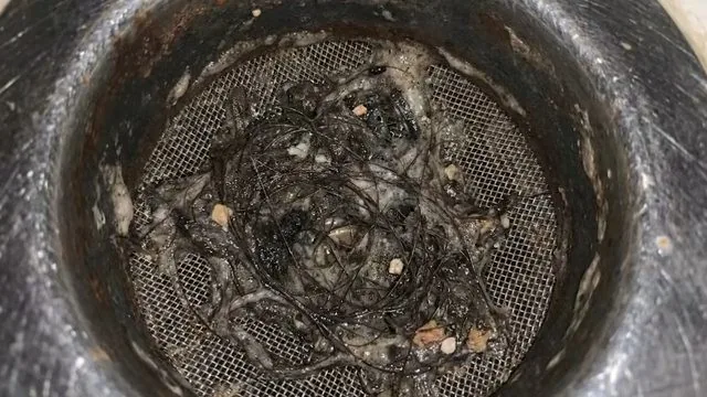 Floor drain strainer packed with hair and debris