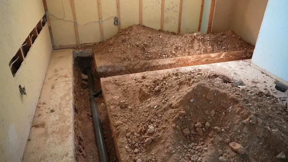 Trench cut through an interior concrete floor with a pipe exposed