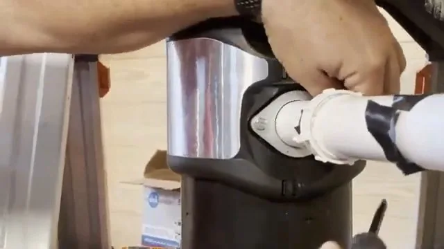 Hands tightening the mounting ring and drain elbow on a new garbage disposer
