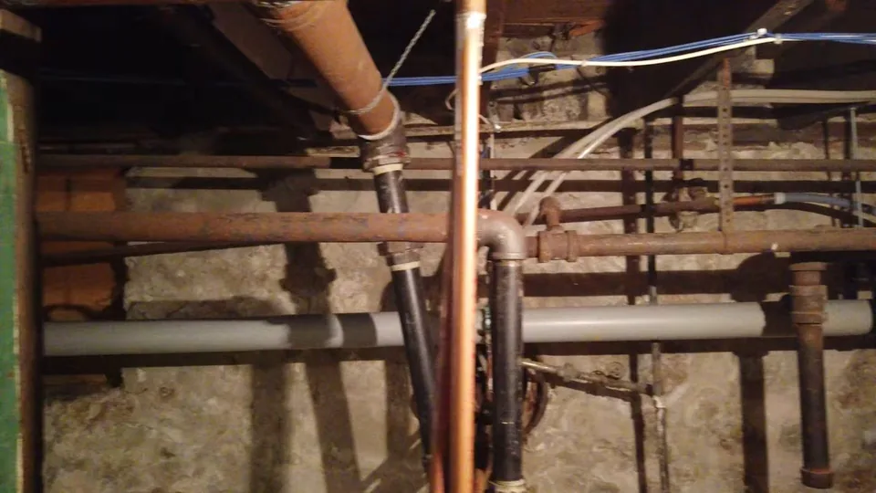 Copper, galvanized and plastic pipes running between joists in a crawl space