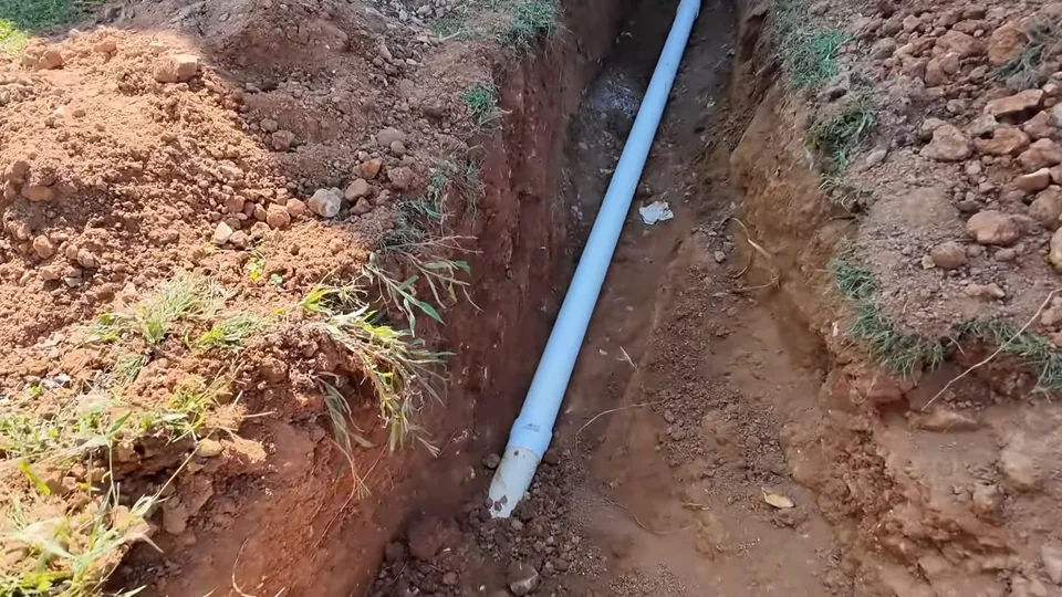 New PVC pipe laid in a trench across a yard