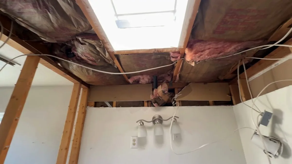 Ceiling opened between joists with damp insulation hanging down