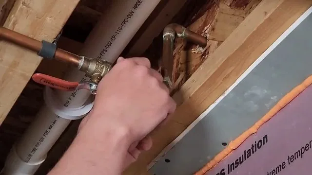 Hand tightening a copper valve joined to PEX inside an open wall cavity