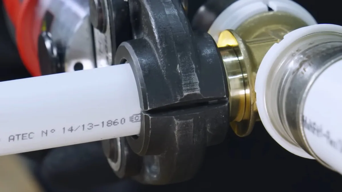 White PEX pipe seated in a press fitting with a brass sleeve