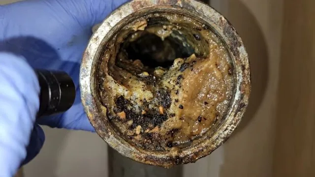 Inside of a drain pipe lined with hardened buildup