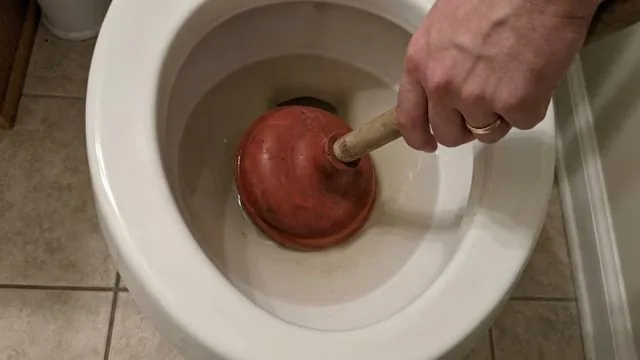 Plunger in a toilet bowl during a clog