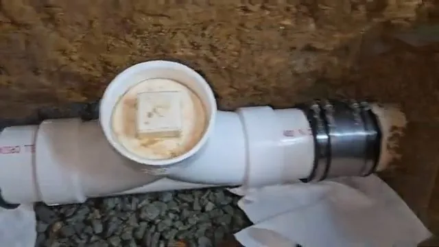 White PVC cleanout tee with its cap seated in an excavated trench