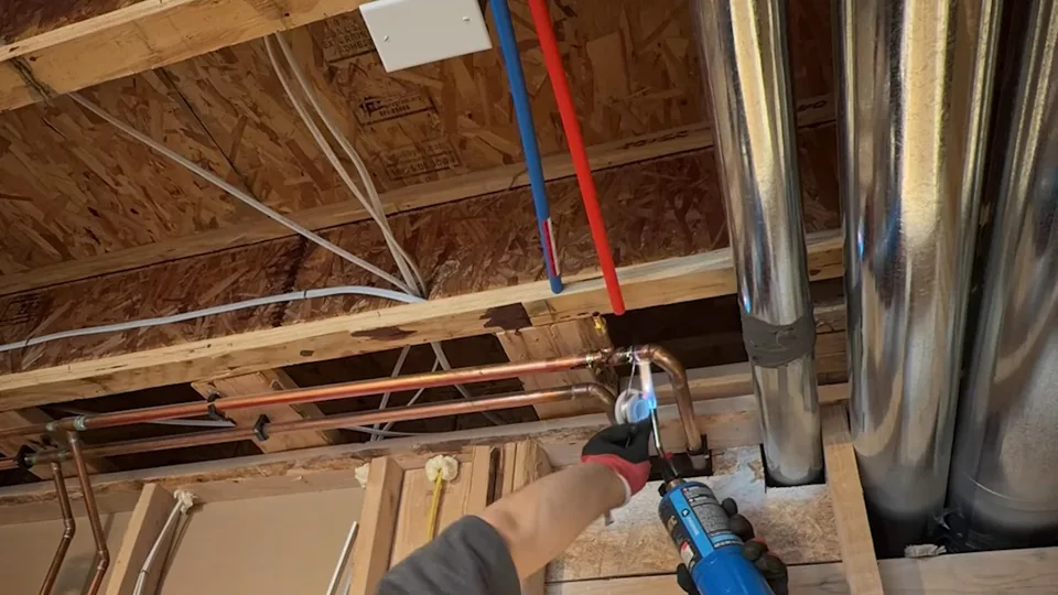 Red and blue PEX supply lines run along an open basement ceiling