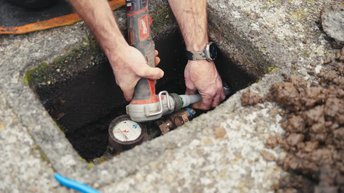 Rotary tool being used on fittings inside an in-ground water meter box