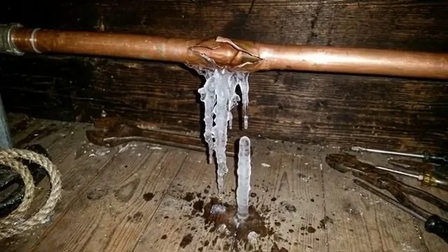 Copper pipe split along a seam with icicles hanging from the opening