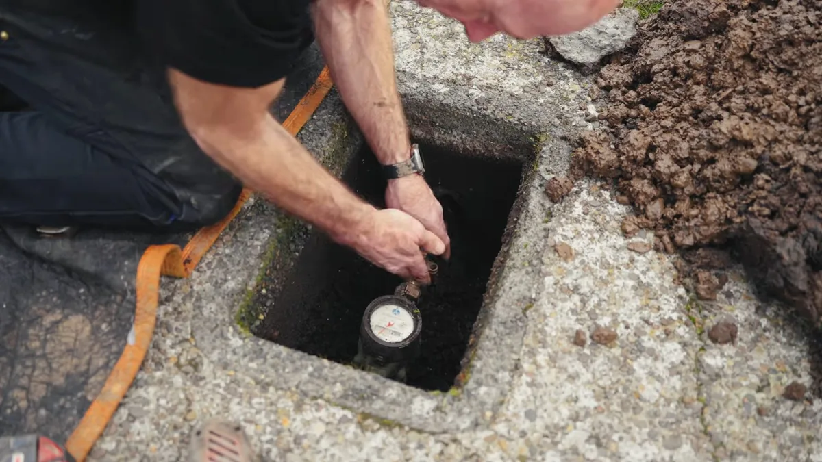 Technician working at an open in-ground water meter box