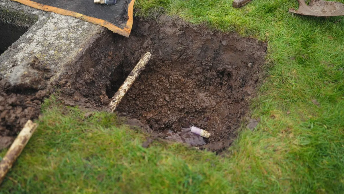 Trench dug across a lawn to reach a buried sewer line