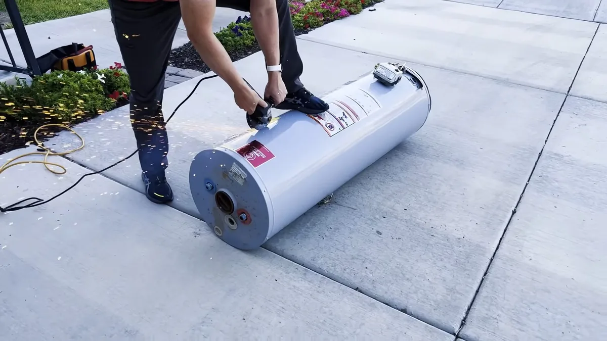 Two people moving a water heater tank along a driveway