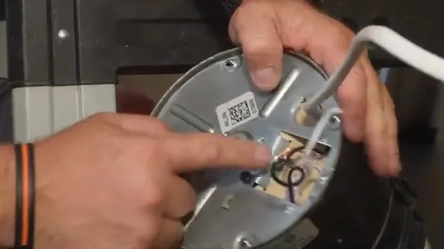 Hands pointing to the label and wiring cover on the underside of a garbage disposer
