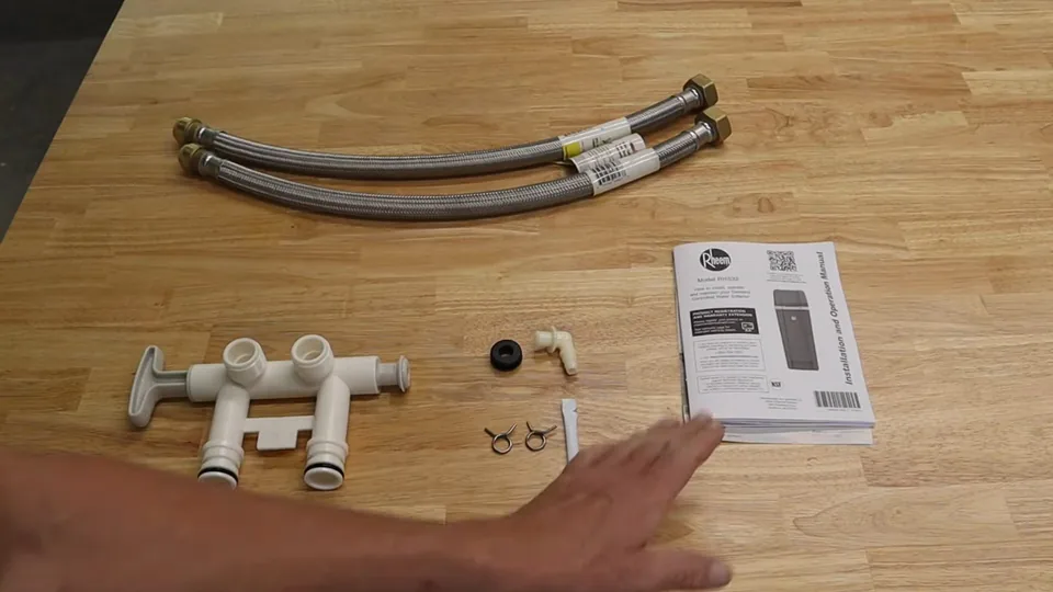 Braided flex connectors, plastic fittings and a manual laid out on a wooden bench
