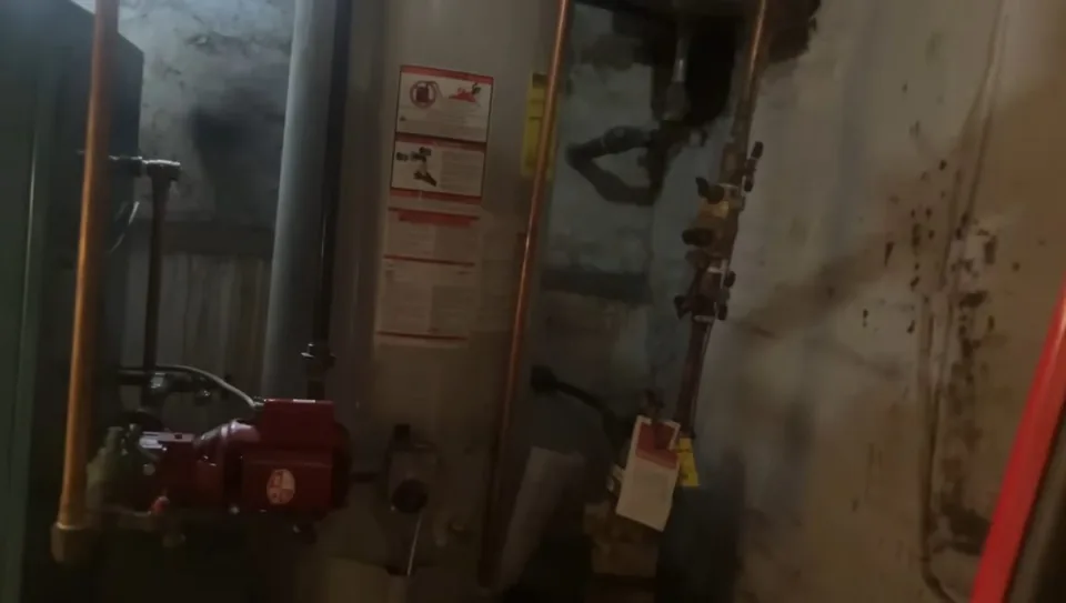 Basement water heater with a red relief valve on its side