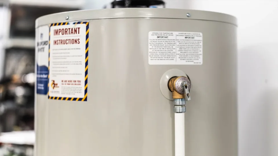 Water heater tank with warning labels and a relief valve fitted with white pipe