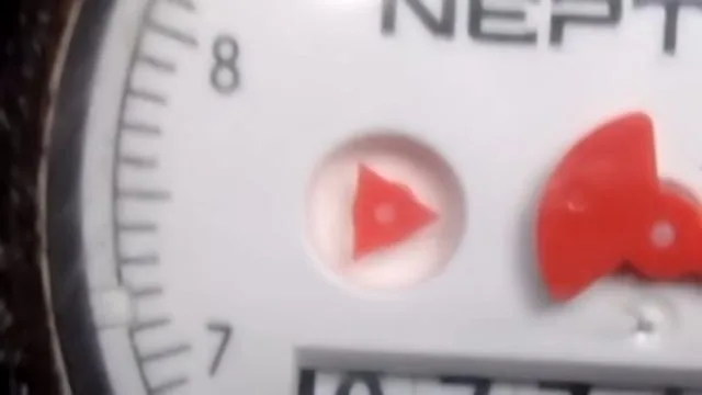 Close-up of a water meter dial with a red triangular leak indicator